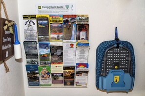 A bulletin board with various travel guides and a blue luggage trolley with a 'PULL' sign.