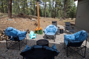 An outdoor seating area with four chairs and a table, surrounded by a gravel ground and trees. - Charming 1-bedroom cottage perfect for a relaxing Durango getaway (Durango)