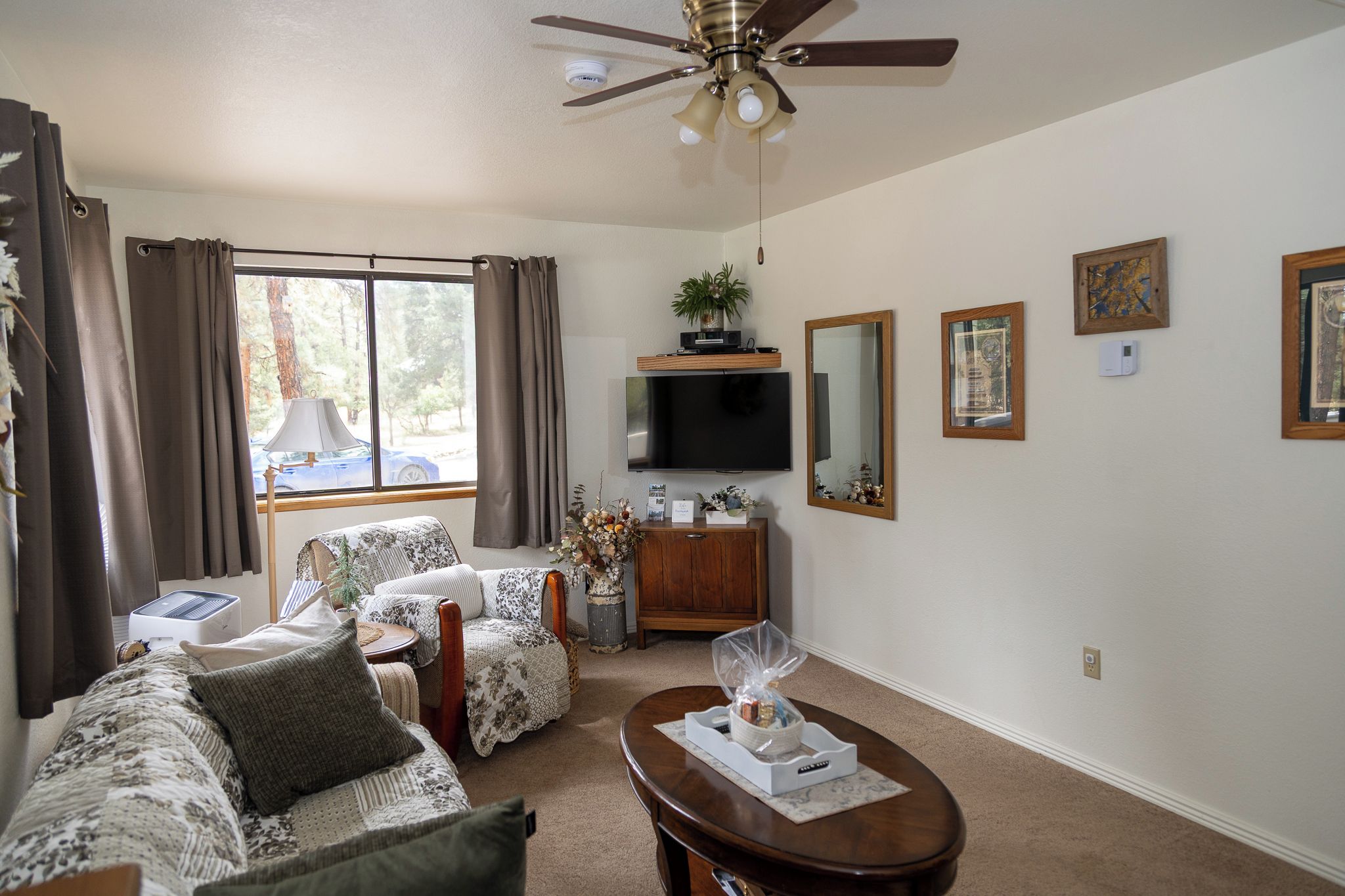 Un salon doté d’un ventilateur de plafond, d’un téléviseur à écran plat, d’une table basse et d’un canapé.