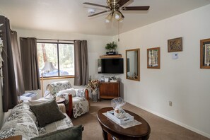 A living room with a ceiling fan, a flat-screen TV, a coffee table, and a sofa.