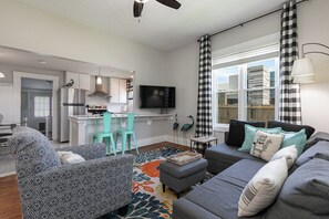 A modern living room with a grey sofa, teal chairs, a coffee table, and a TV. - Bright & Beautiful Turn-of-the-Century Modern Home (Springfield)