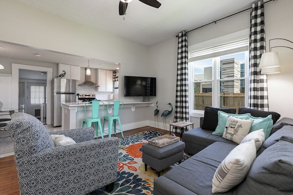 A modern living room with a grey sofa, teal chairs, a coffee table, and a TV.
