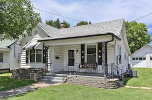 A white single-story house with a porch, stone steps, and a chimney.