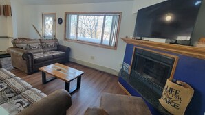 Een woonkamer met een open haard, een televisie en een bank.