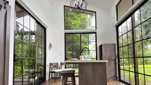 Une cuisine moderne dotée de grandes fenêtres, d’un îlot central et d’un coin repas avec des chaises.