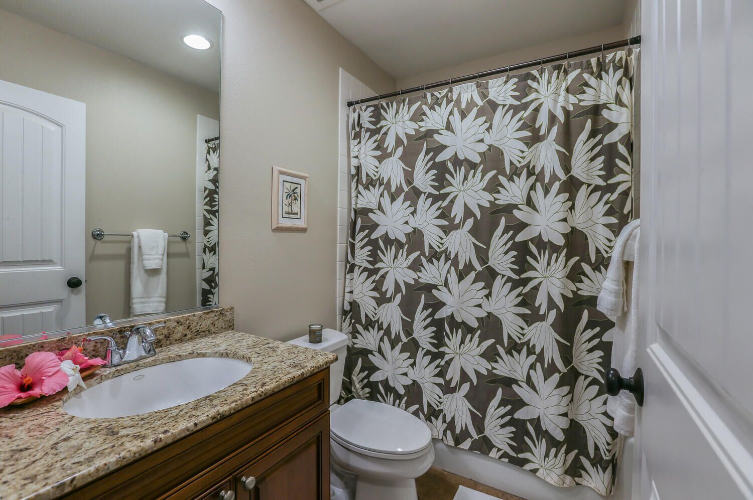 Ein Badezimmer mit zwei Waschbecken, einer Toilette und einer Duschkabine mit Blumenmuster.