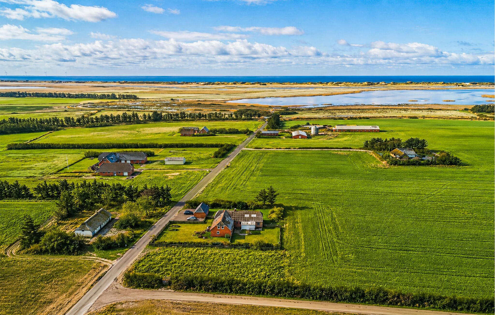 A rural landscape with fields, a road, and buildings.