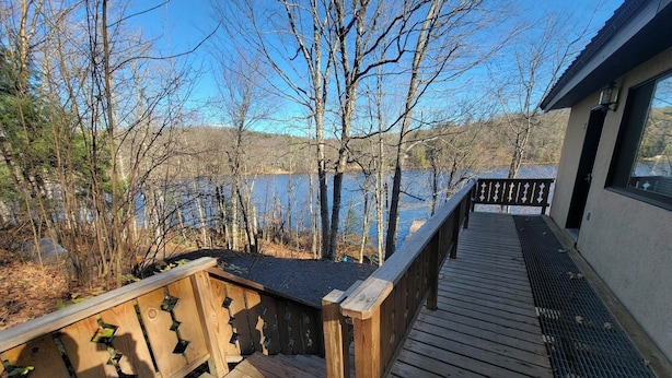 A wooden deck with a railing overlooking a body of water and trees. - LAKEFRONT 3-bedroom Chateau Getaway at Whitecap Mountains Resort Unit 2 (Upson)