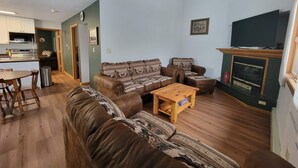 A cozy living room with a brown leather sofa, a wooden coffee table, and a fireplace. - LAKEFRONT 3-bedroom Chateau Getaway at Whitecap Mountains Resort Unit 2 (Upson)
