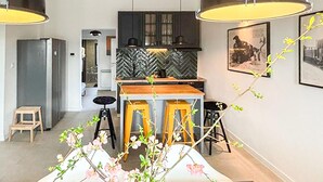 Eine moderne Küche mit Fischgrätmuster-Spritzschutz, Holzbarhocker und Pendelleuchten.