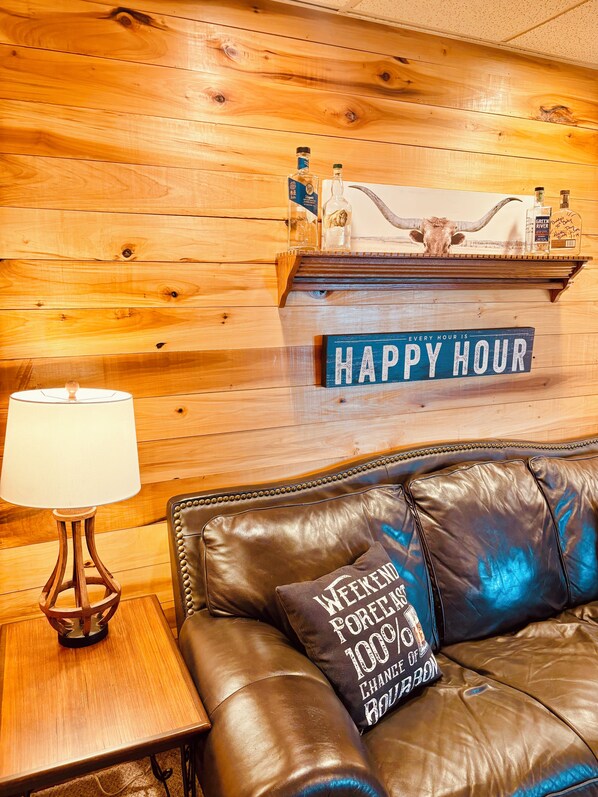 A wooden wall with a shelf displaying bottles and a sign that reads 'HAPPY HOUR'.