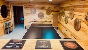A ping pong table in a room with wooden walls and various whiskey barrel logos.