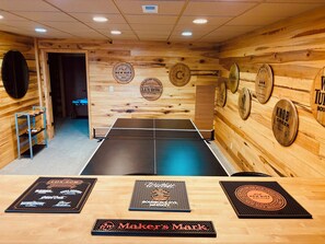 A ping pong table in a room with wooden walls and various whiskey barrel logos.