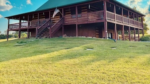 A large wooden building with a green roof, a staircase leading to a porch, and an American flag.