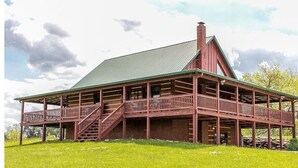 Un grand bâtiment rustique en bois, doté d’un toit vert, de nombreux balcons et d’un escalier menant aux étages supérieurs.