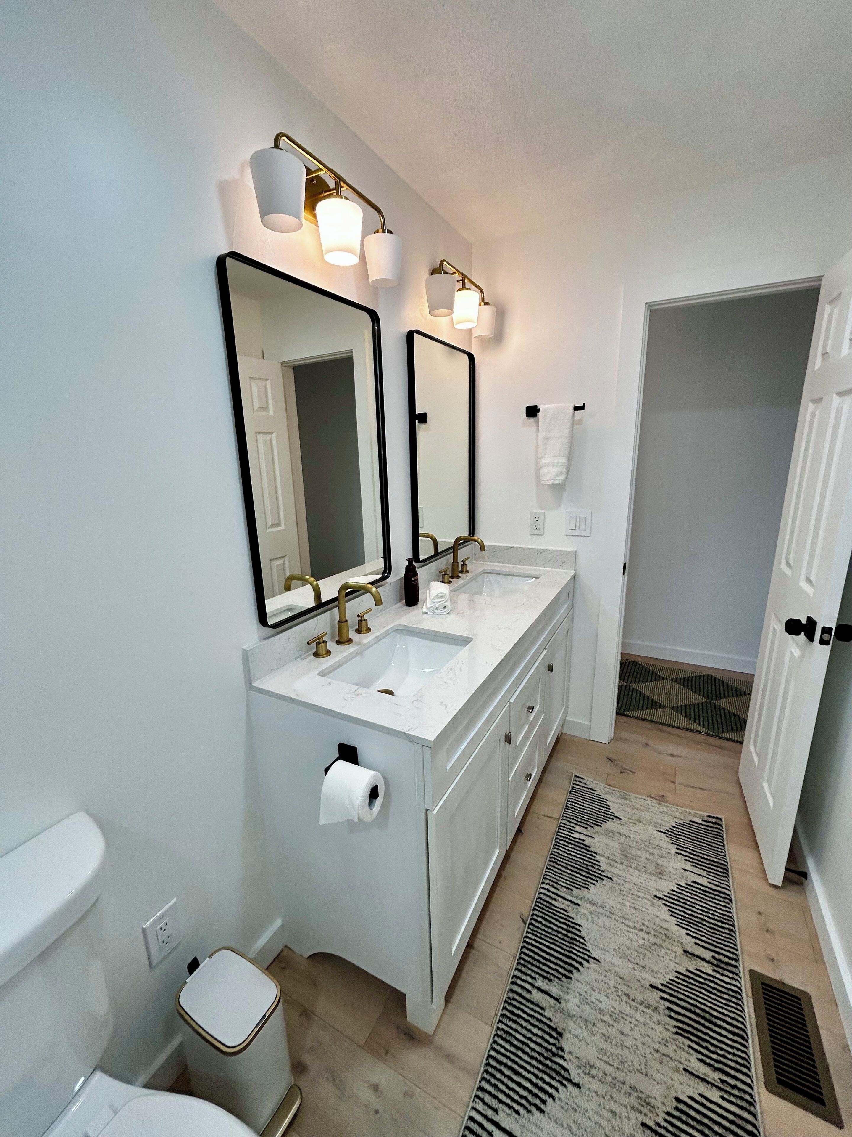 Une salle de bain moderne avec deux lavabos, des toilettes et un miroir.