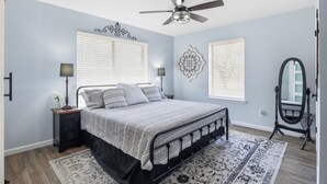 A bedroom with a bed, two bedside lamps, a ceiling fan, and a large mirror. - Quiet Farm, Gameroom, Firepit 2 Mi to McKinney (McKinney)