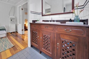 Ein Badezimmer mit einem Holztisch, einem Spiegel und einer Vase mit Blumen.