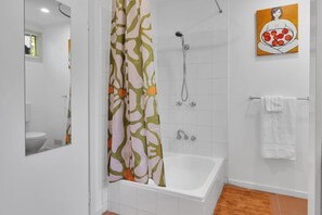 Un baño con ducha, bañera, inodoro y un perchero para toallas.