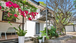 A residential building with a balcony, potted plants, and a staircase. - Birdwing Retreat (Picnic Bay)
