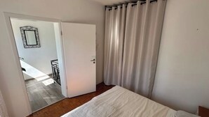 Un dormitorio con cama, una puerta y una cortina.