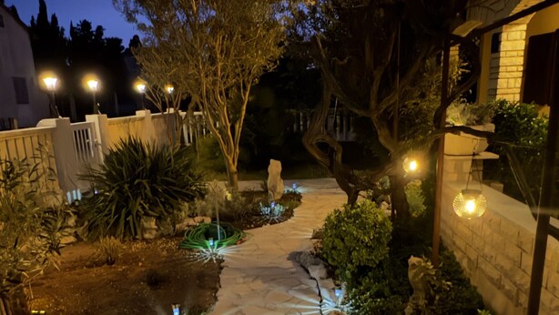 Un sendero de piedra que atraviesa un jardín con árboles e iluminación decorativa.