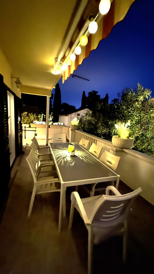 An outdoor dining area with a table and chairs, a potted plant, and a view of the sky.