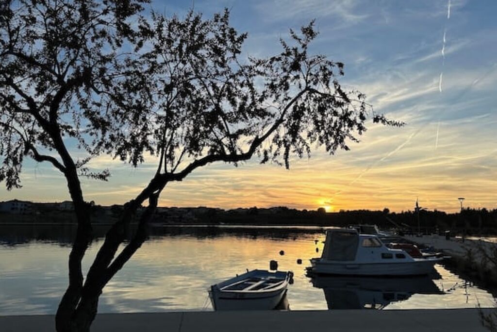 A sunset over a calm body of water with boats docked nearby.