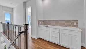 Una cocina moderna con armarios blancos, un salpicadero de azulejos hexagonales y piso de madera.