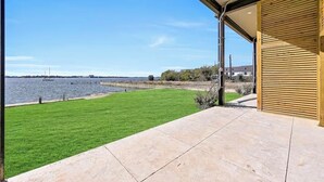 Un patio con vista al agua, un césped y una estructura de madera.
