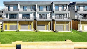 Un edificio residencial moderno de varios pisos con balcones, ventanas grandes y puertas de garaje.