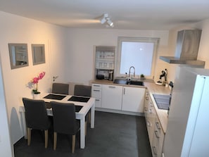 A compact kitchen with a dining table, chairs, a sink, and a window. - Apartment D&Y ground floor (barrier-free) (Ubstadt-Weiher)