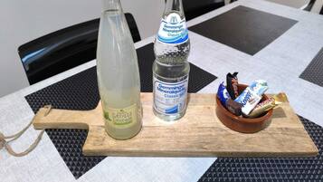 Ein Tisch mit einer Flasche Zitronenlimonade, einer Flasche Mineralwasser und einer Schüssel Snacks.