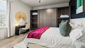 Ein modernes Schlafzimmer mit Bett, Schreibtisch, Stuhl, Kleiderschrank und Deckenventilator.