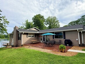 A house with a patio, a table, chairs, a grill, and a view of a lake. - Weiss Choice - NEW RENTAL -charming lake house with stunning views (Leesburg)