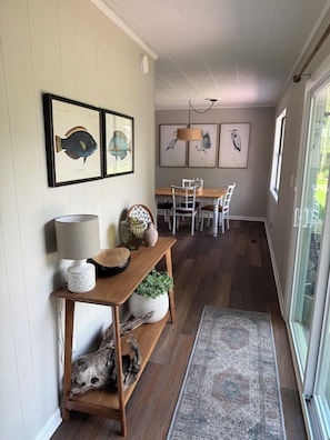 A dining area with a wooden table and chairs, a hanging light fixture, and framed artwork on the wall. - Weiss Choice - NEW RENTAL -charming lake house with stunning views (Leesburg)