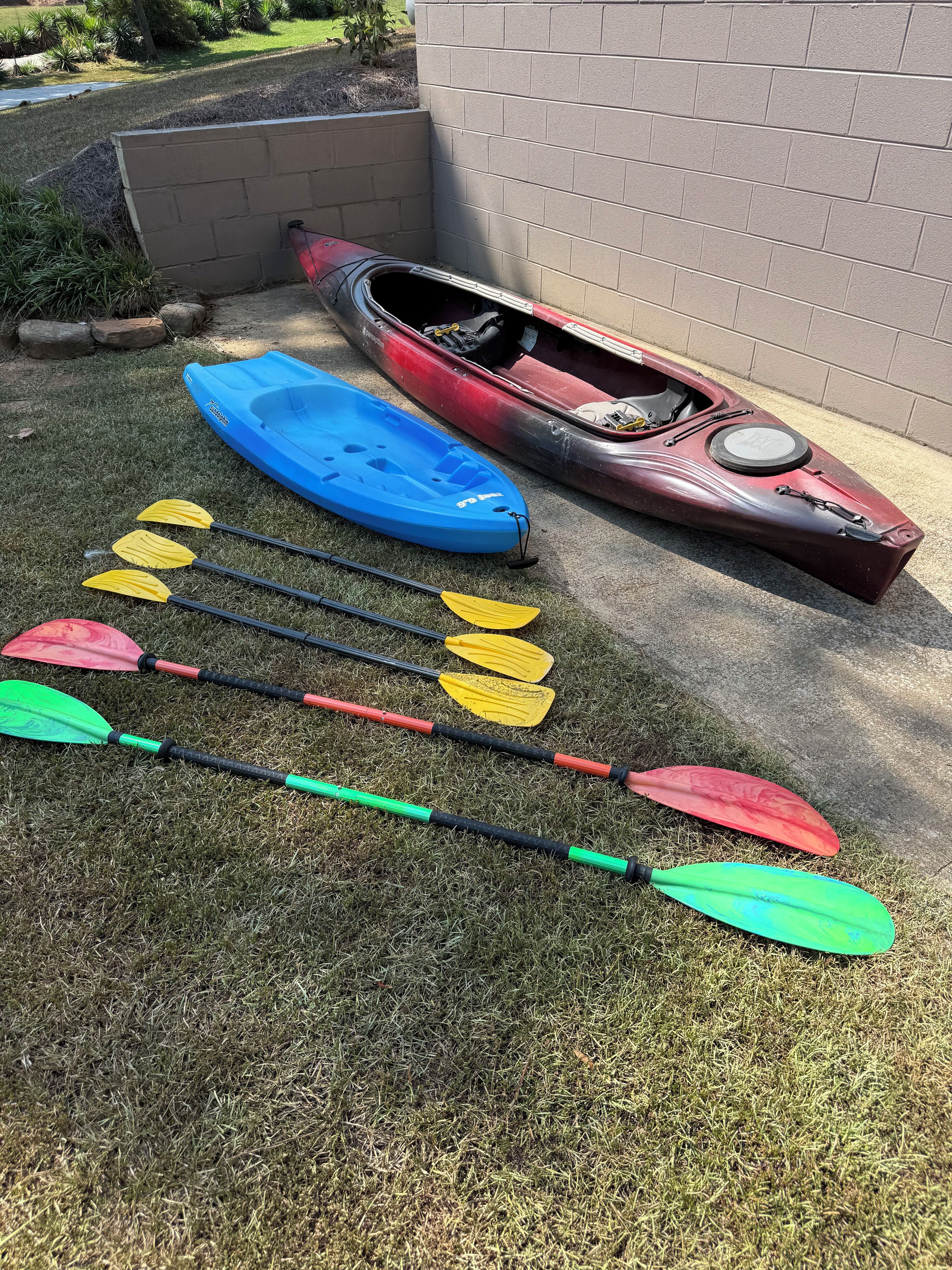 Kayaks and paddles on a grassy area near a building.