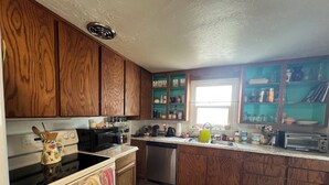 A kitchen with wooden cabinets, a stove, microwave, dishwasher, and a window with a view. - Kid & Pet-Friendly Rainbow Cottage in the Heart of Arco (Arco)