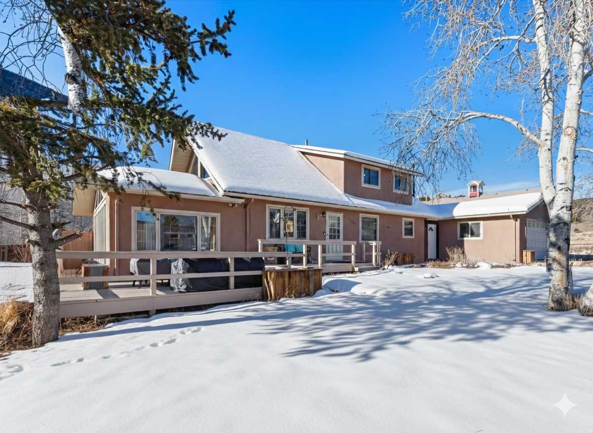 Una casa de dos pisos con un porche cubierto, un garaje y un camino de entrada cubierto de nieve.