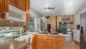 Une cuisine moderne avec des meubles en bois, un grand îlot central et un coin repas offrant une vue agréable.