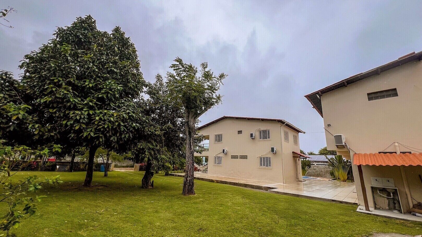 A building with a flat roof and multiple windows, surrounded by a well-maintained lawn and trees.