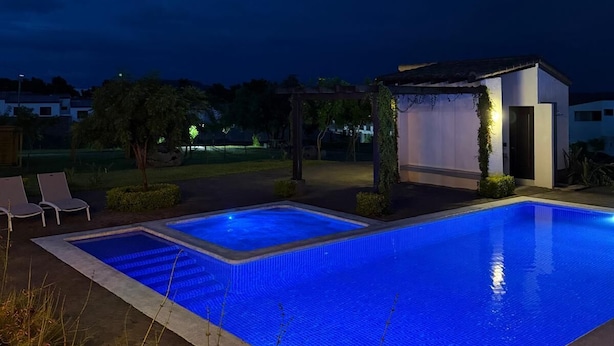 Una piscina con superficie d'acqua cristallina, circondata da sdraio e una pergola.