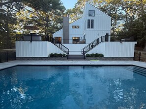 A modern house with a swimming pool, a staircase leading to the entrance, and a fenced yard. - A Modern, Ultra Chic 5-bedroom Beach Home in Charming East Hampton! (East Hampton)