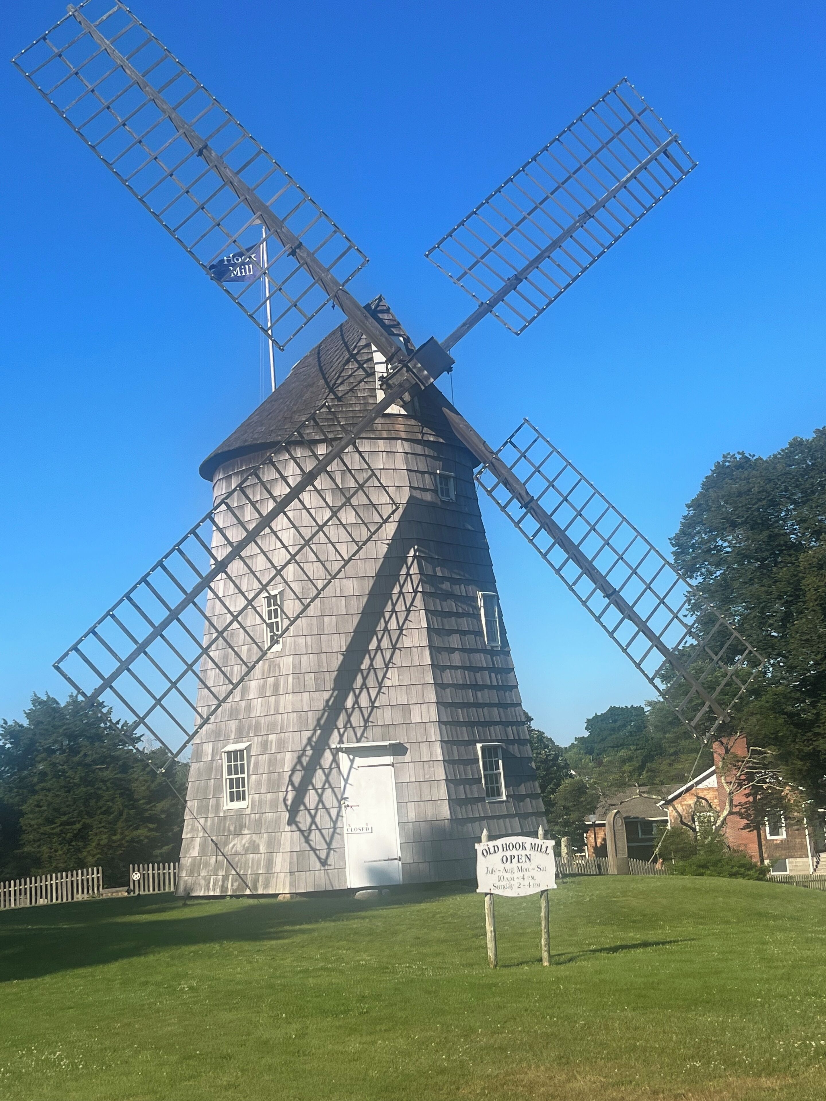 A traditional windmill with a sign indicating it is open on weekdays.