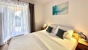 Hotelkamer met een groot bed, een nachtkastje met lamp en uitzicht buiten door een raam met gordijnen.