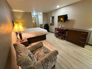 Ein Hotelzimmer mit Bett, Schreibtisch, Stuhl, Fernseher und Lampe.