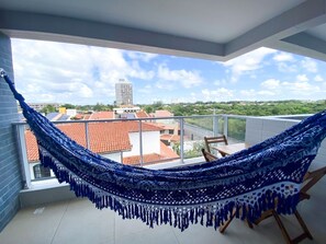 Eine Hängematte auf einem Balkon mit Blick auf Gebäude und einen klaren Himmel.