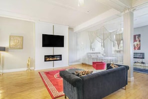 A modern living room with a flat-screen TV, fireplace, and a red rug.