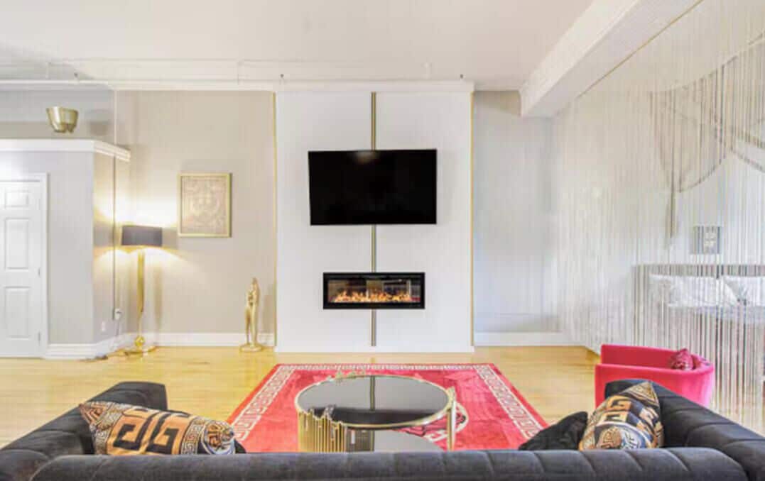 Una sala de estar con chimenea, televisor de pantalla plana, sofá y alfombra roja.