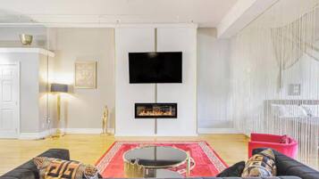Una sala de estar con chimenea, televisor de pantalla plana, sofá y alfombra roja.